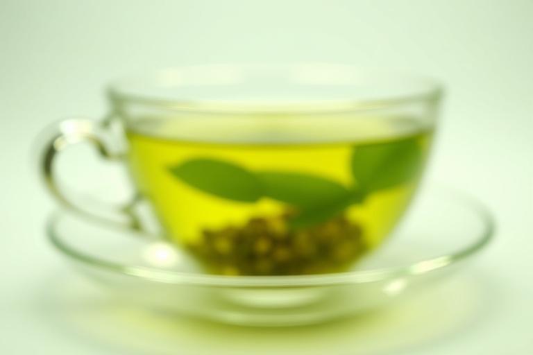 Close-up shot of green tea leaves steeping in a delicate teacup, symbolizing focus and clarity.